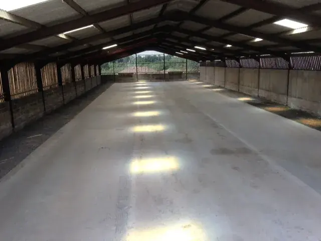 Inside the indoor storage building: a long swept concrete floor under a steel-framed roof, daylight coming through the open end.