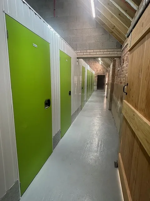 Inside the converted barn: the corridor of storage rooms with bright green doors.